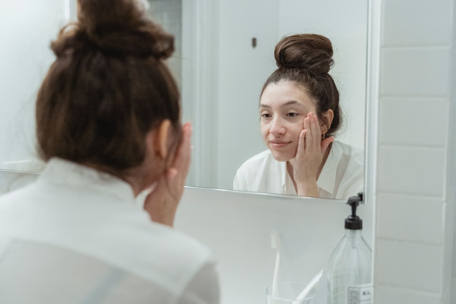 Woman applying skincare in front of her bathroom mirror