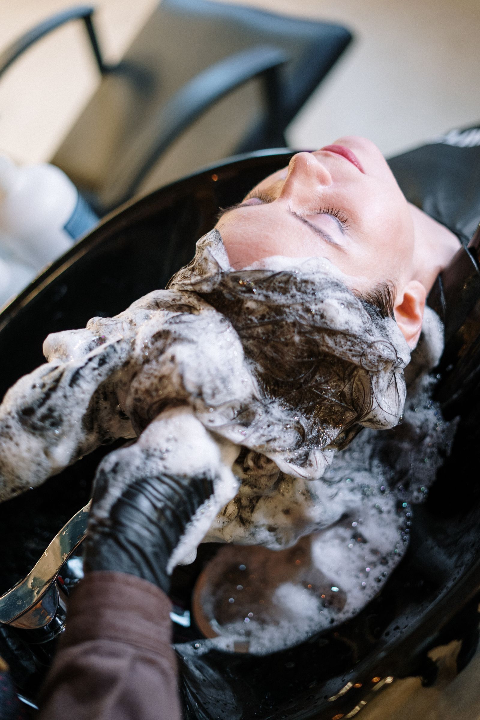 Stylist washing a woman's hair at a salon sink